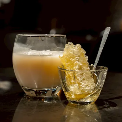 グラスに注がれたマッコリに巣ごとのハチミツが添えられた一枚です