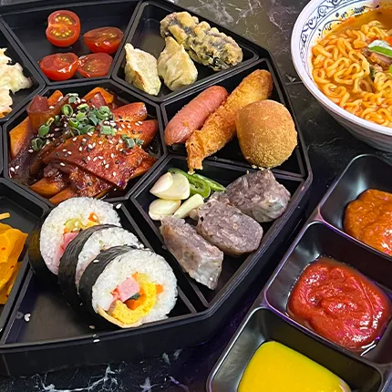 黒いプレートの上に韓国の揚げ物やキンパ、ソーセージなどが彩りよく盛り付けられています