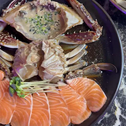 黒い皿の上に新鮮なサーモンと醤油漬けのカニが美しく盛られた、鮮度を感じる一皿です