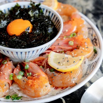 醤油漬けのエビが卵黄と海苔を添えて美しく盛られた、食欲をそそる一皿です