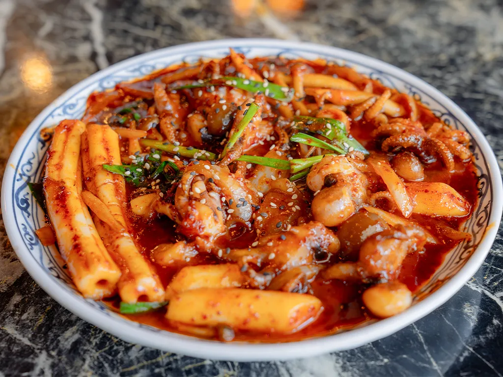 赤い辛いタレで炒めたイイダコとトッポギが皿に盛られている