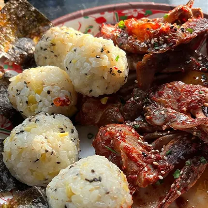 ヤンニョムケジャンと香ばしい海苔、丸いおにぎりが皿に彩りよく盛り付けられています